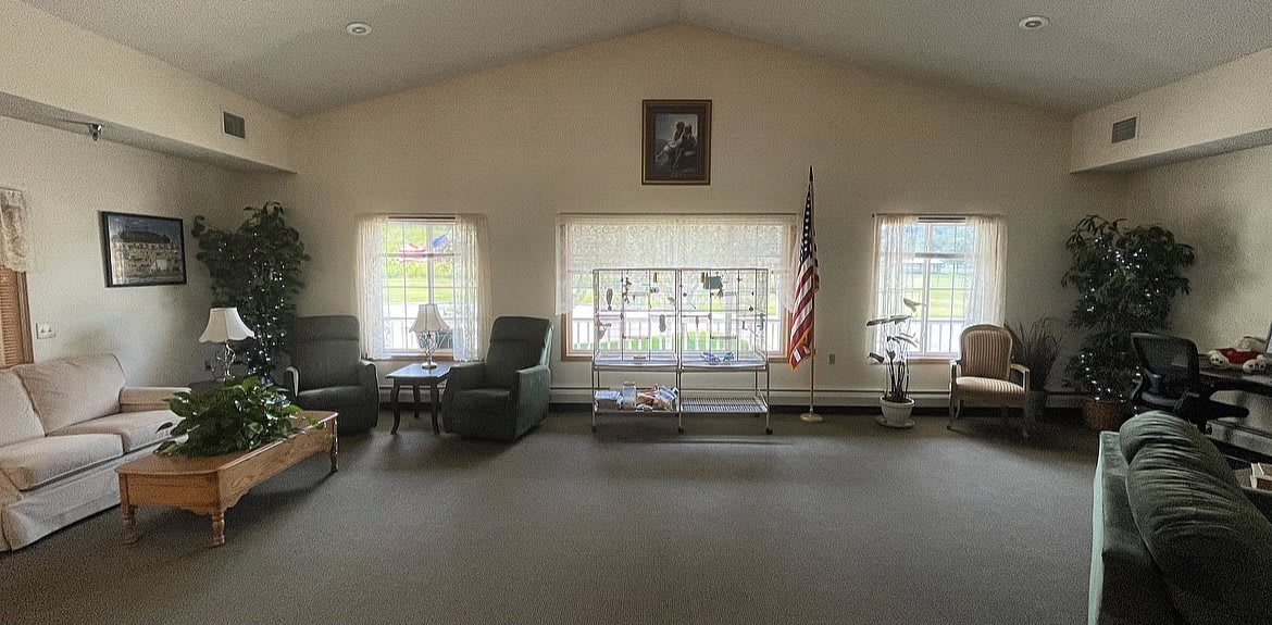 A quiet living room with chairs, large windows, and an American flag.