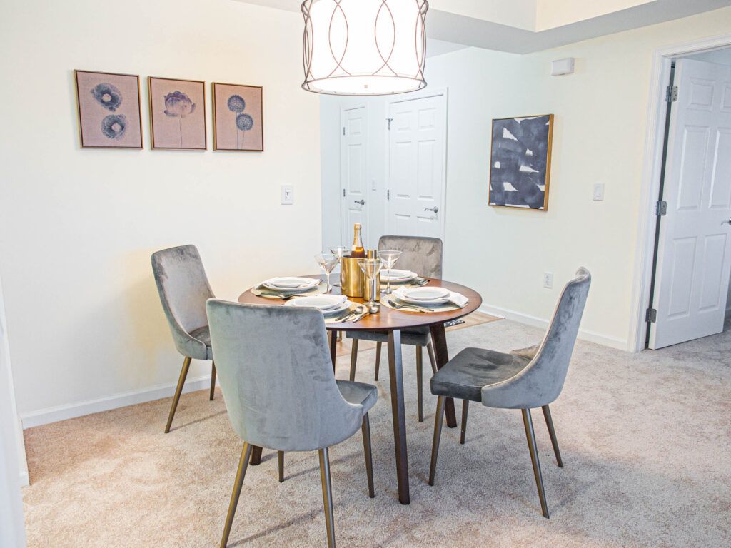 A modern dining room with a round table and upholstered chairs, featuring tasteful wall art.