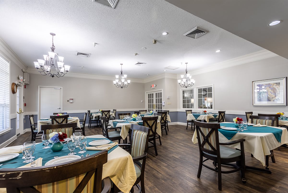 An elegantly decorated dining area with neatly arranged tables and chairs, enhanced by chandelier lighting.