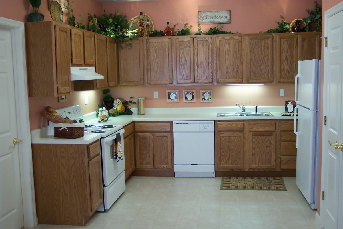 A cozy kitchen with wooden cabinets, white appliances, and decorative items on the upper shelves.