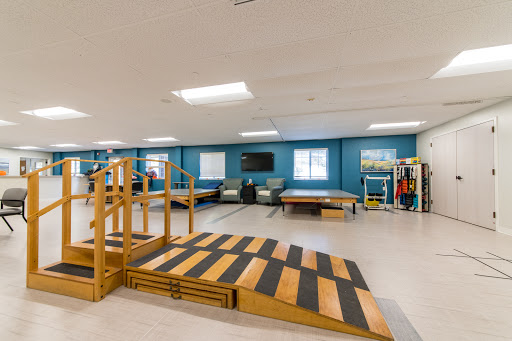 A spacious therapy room equipped with a wooden ramp and exercise areas for rehabilitation.