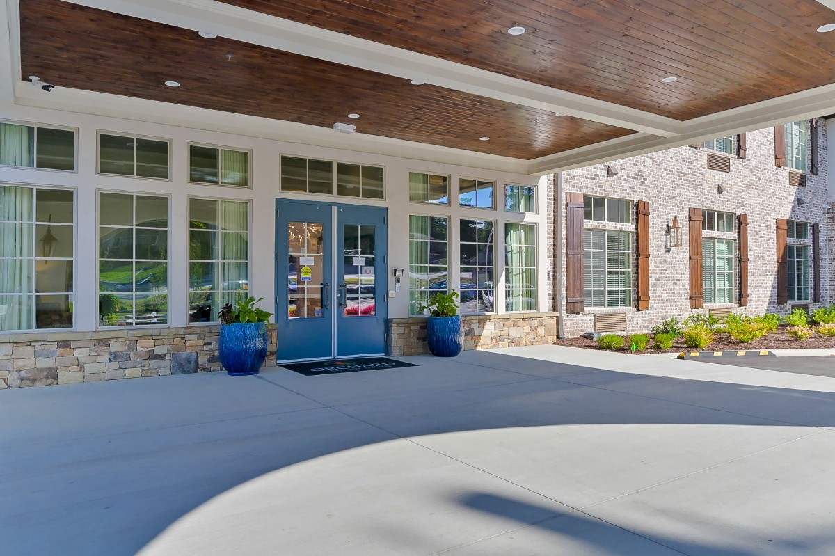 Front entrance of a modern building with blue double doors and potted plants.