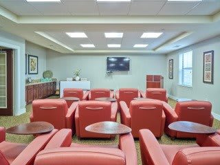 A cozy lounge area with red chairs and a television on the wall.