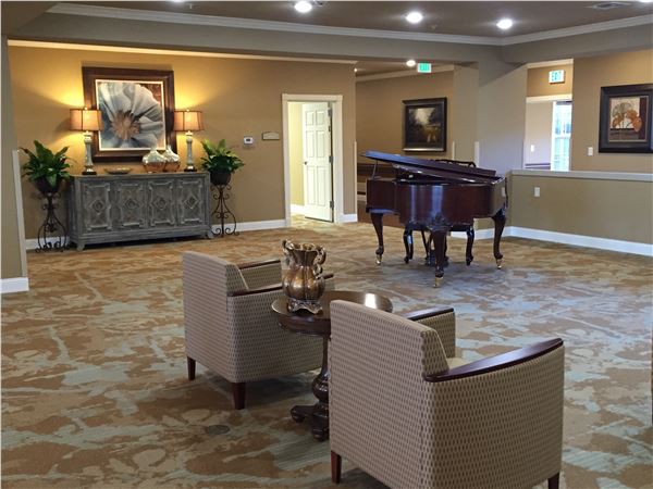 A spacious and elegantly decorated living room featuring a grand piano and comfortable seating.