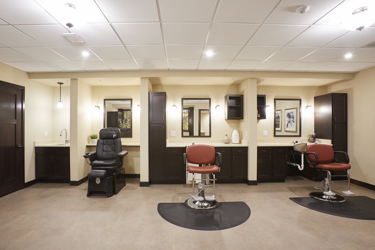 An empty barber shop with several chairs and mirrors lined up along the wall.