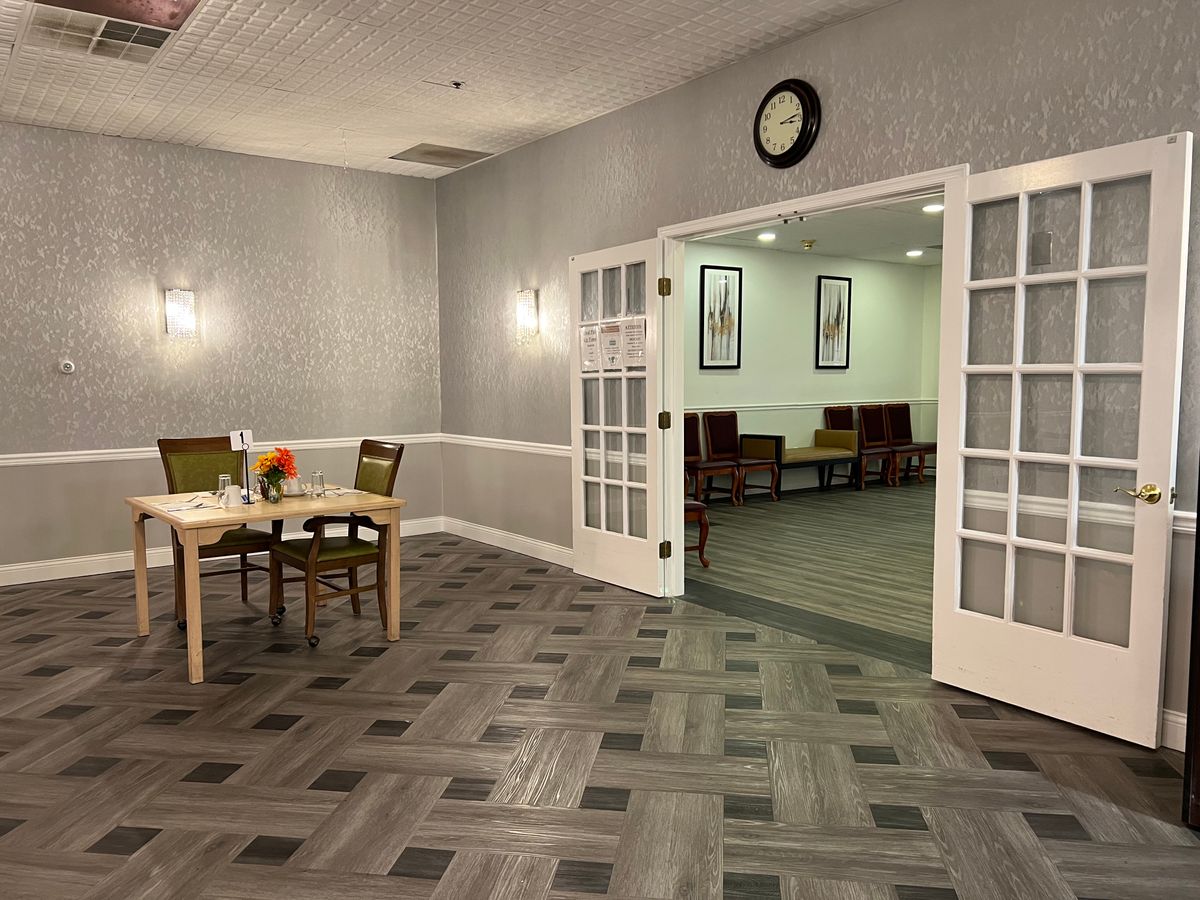 A modern waiting room with a seating area visible through open double doors.