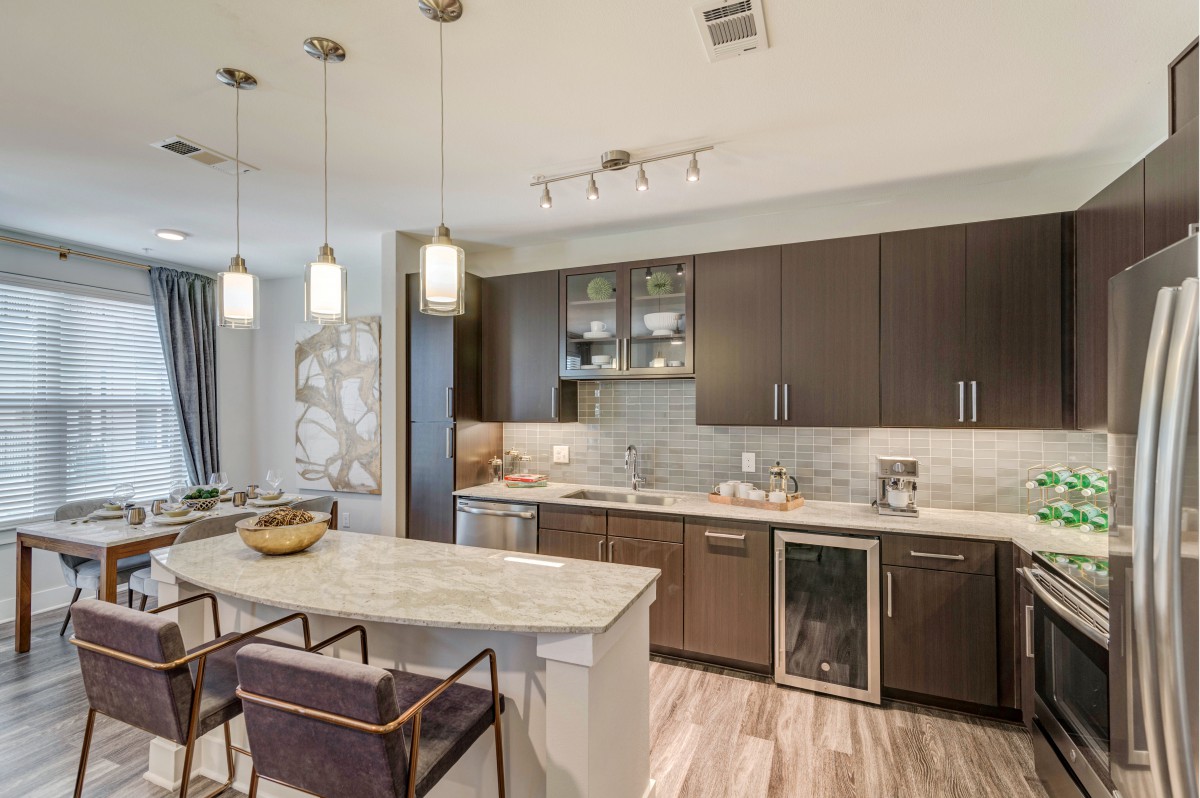 A modern kitchen with an open concept design featuring a central island, pendant lighting, and stainless steel appliances.