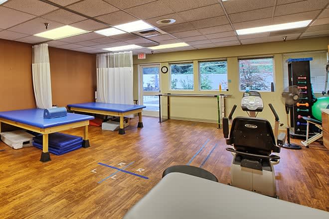 A physical therapy clinic with therapy beds and rehabilitation equipment.