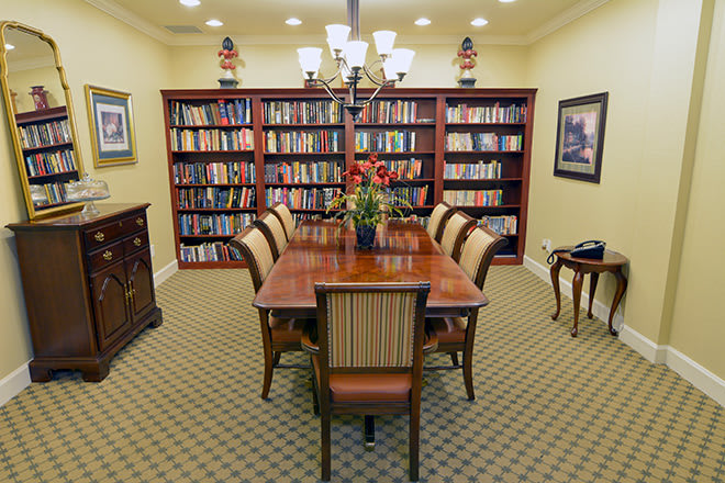 A cozy library room with a wooden dining table and chairs surrounded by bookshelves.