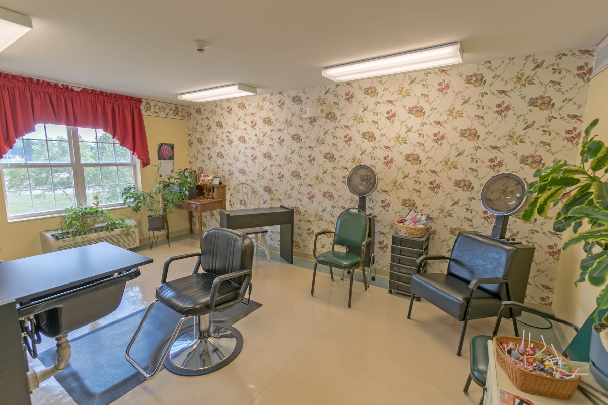 A cozy salon interior with chairs, hair dryers, and floral wallpaper.