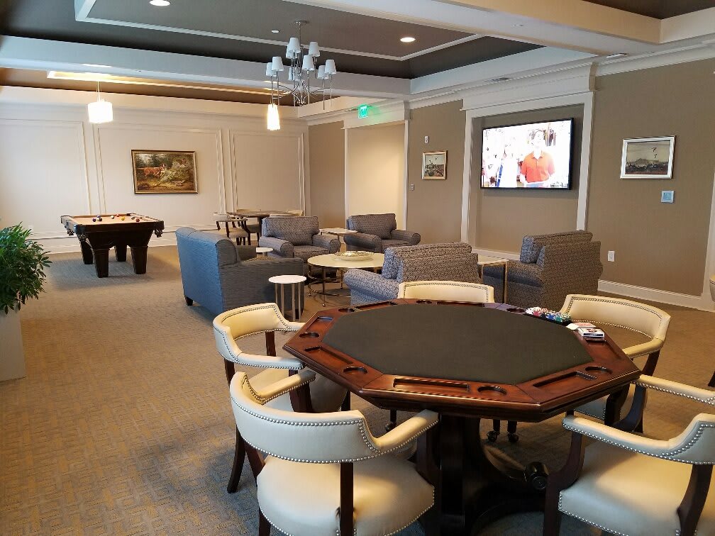 A stylish lounge area featuring a poker table, comfortable seating, and a television.