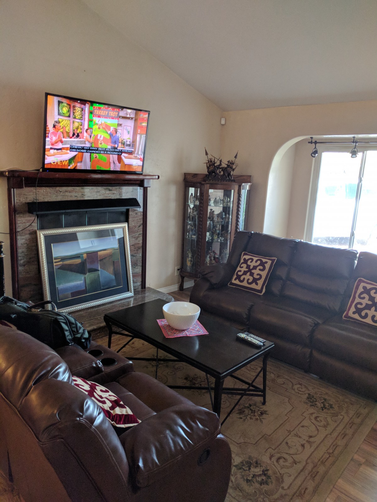 A cozy living room with a sofa, coffee table, and a TV mounted above the fireplace.
