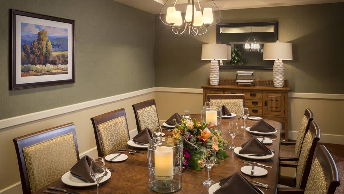A beautifully set dining room table with elegant decor, including a chandelier, candles, and a floral centerpiece.