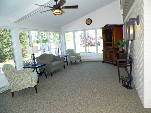 A bright and spacious sunroom with comfortable seating, large windows allowing natural light, and a ceiling fan.