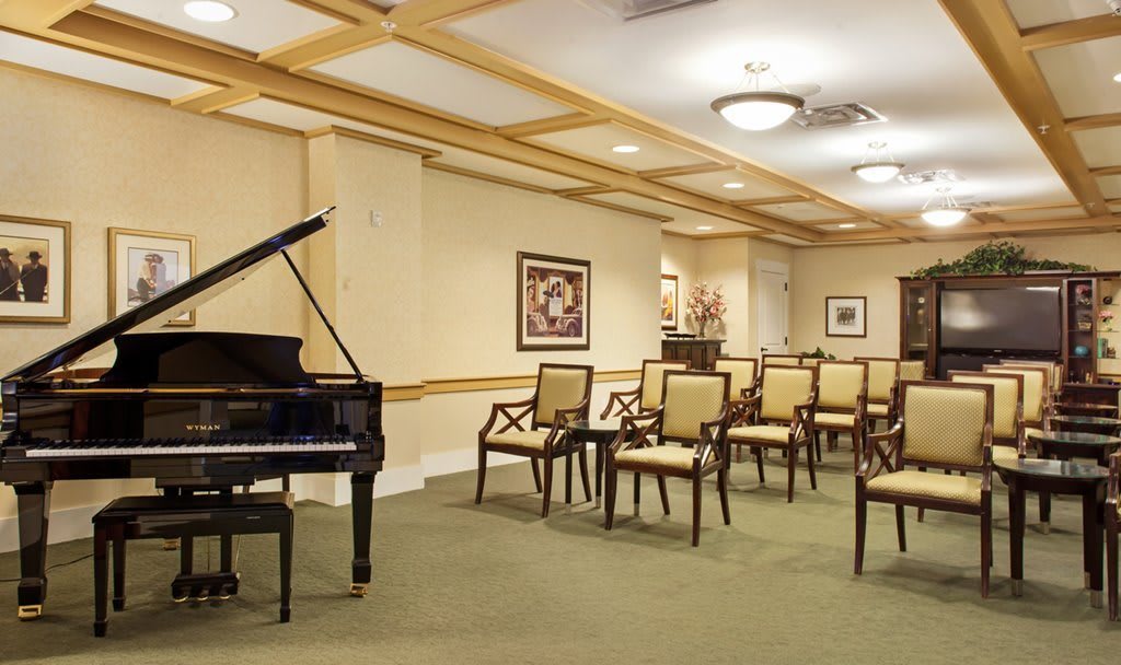 A well-appointed room featuring a grand piano and neat rows of chairs, suitable for concerts or meetings.