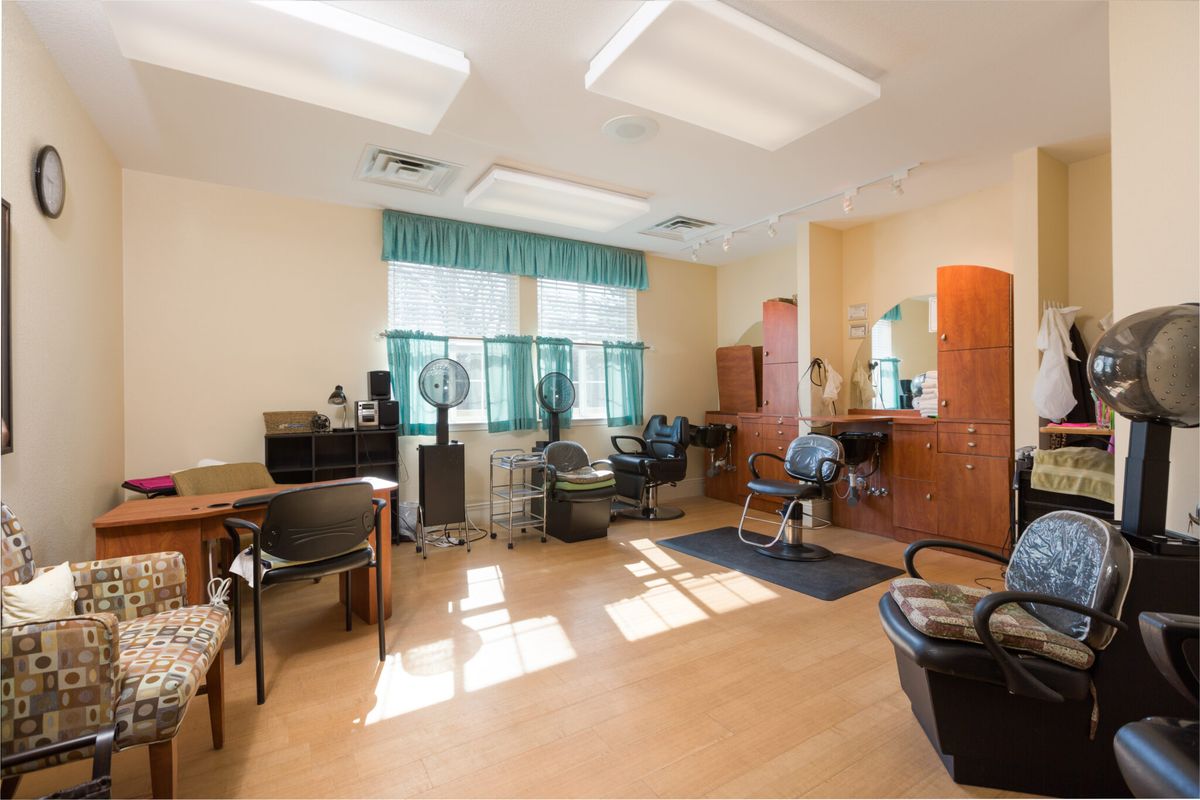A well-lit hair salon interior with chairs, mirrors, and hairdressing equipment.