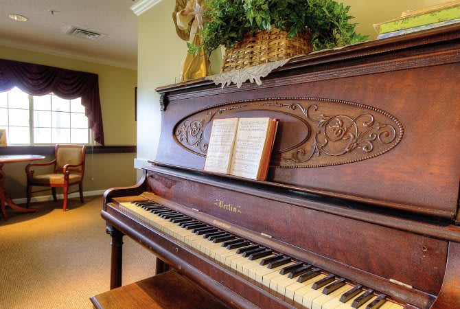 An elegant vintage piano with sheet music, adorned with a floral arrangement on top.