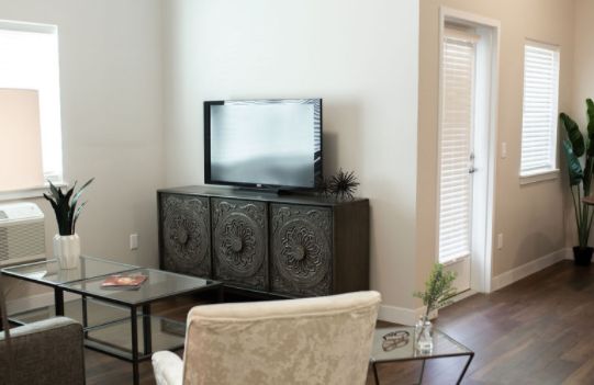 A modern living room featuring a cabinet with a TV on top, accompanied by a chair and side table.
