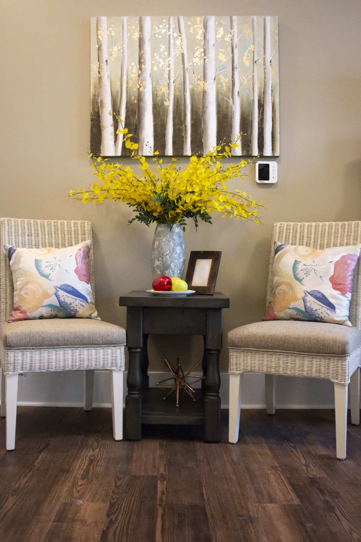 A cozy sitting area with two chairs, a small table, and a decorative flower arrangement.