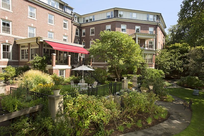 A beautiful residential apartment building with a lush garden and patio area.