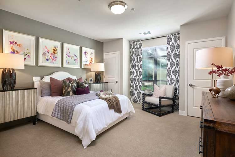 A modern bedroom with stylish decor, featuring a comfortable bed, decorative artwork, and patterned curtains.