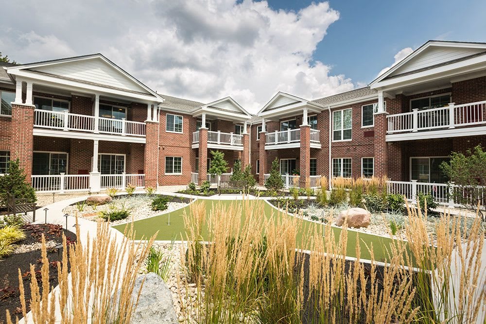 A modern apartment building with well-maintained landscaping under a cloudy sky.