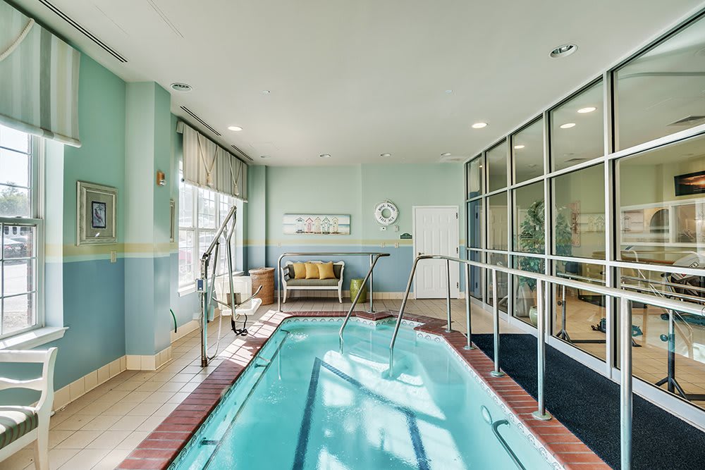 A modern indoor therapy pool with handrails and seating area.