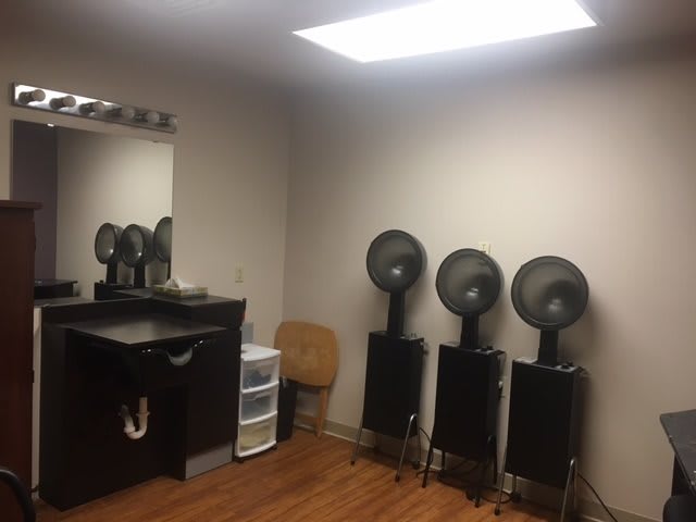 A beauty salon with hair dryers and a styling station.