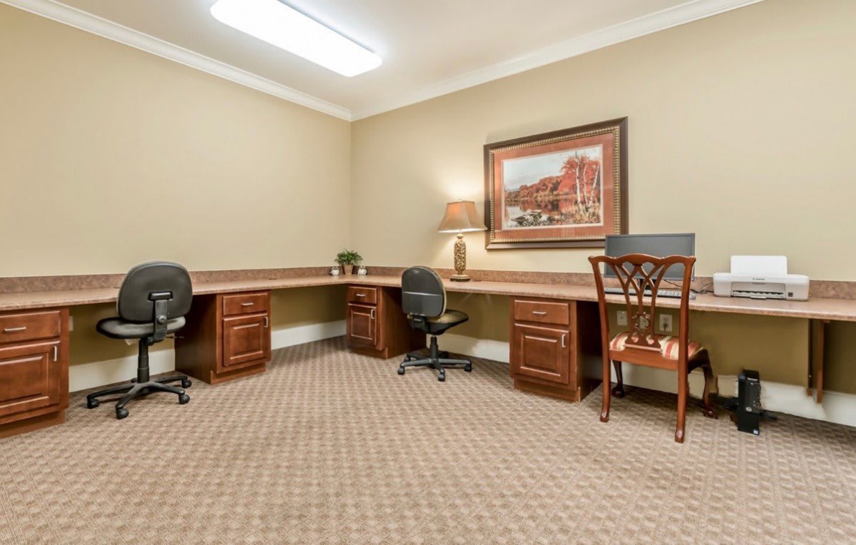 An empty office space with desks, chairs, and a wall painting.