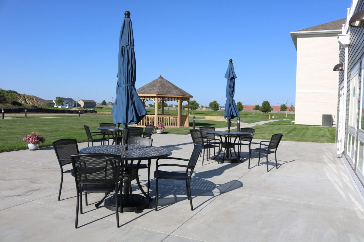 Outdoor patio area with tables, chairs, and umbrellas near a gazebo.