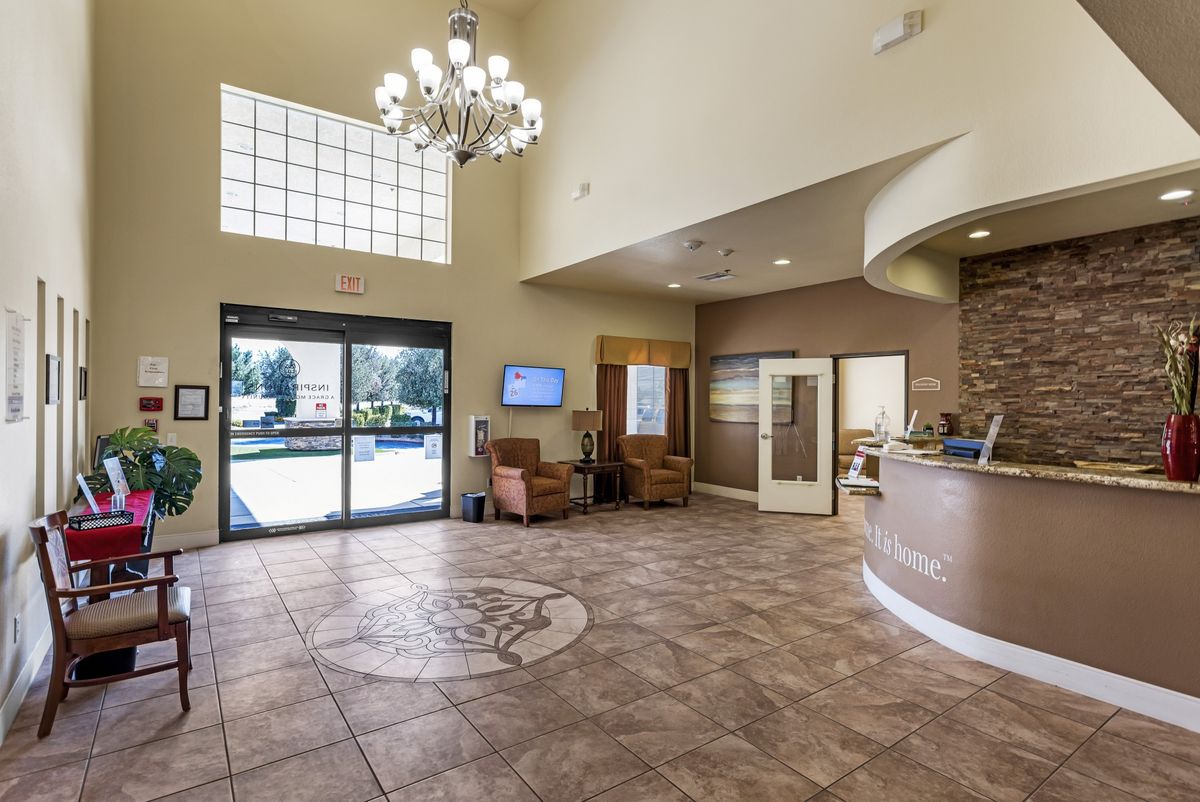 A spacious lobby with a chandelier, seating area, and a reception desk.