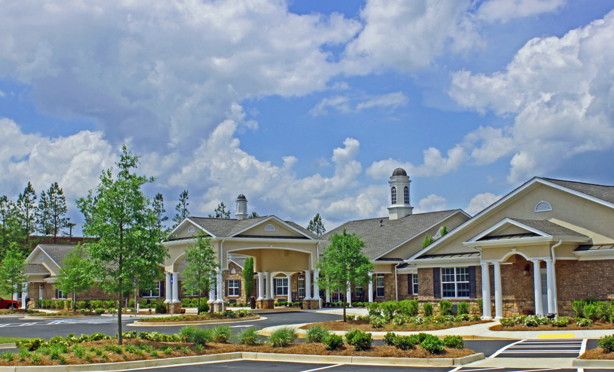 A scenic view of a large building complex under a partly cloudy sky with surrounding trees.