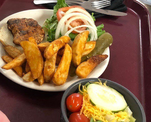 A delicious plate featuring seasoned fries, a fresh salad with tomatoes and onions, and a side of pickles.