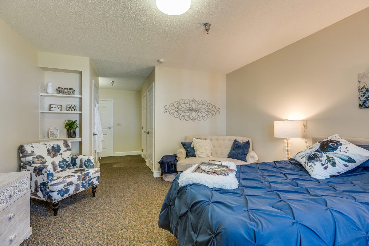 A cozy, modern bedroom featuring a neatly made bed with blue bedding, decorative pillows, and a lamp.
