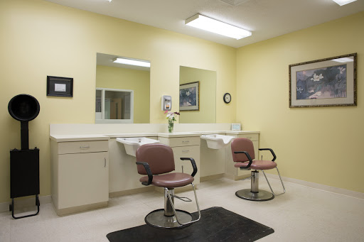 A clean and simple hair salon featuring two styling chairs, mirrors, and a bright yellow interior.