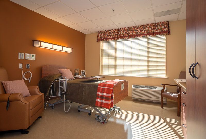 A well-lit hospital room with a comfortable bed and seating area.