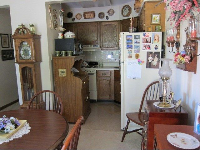 A cozy kitchen and dining area with traditional wooden furniture and a refrigerator adorned with magnets and photos.