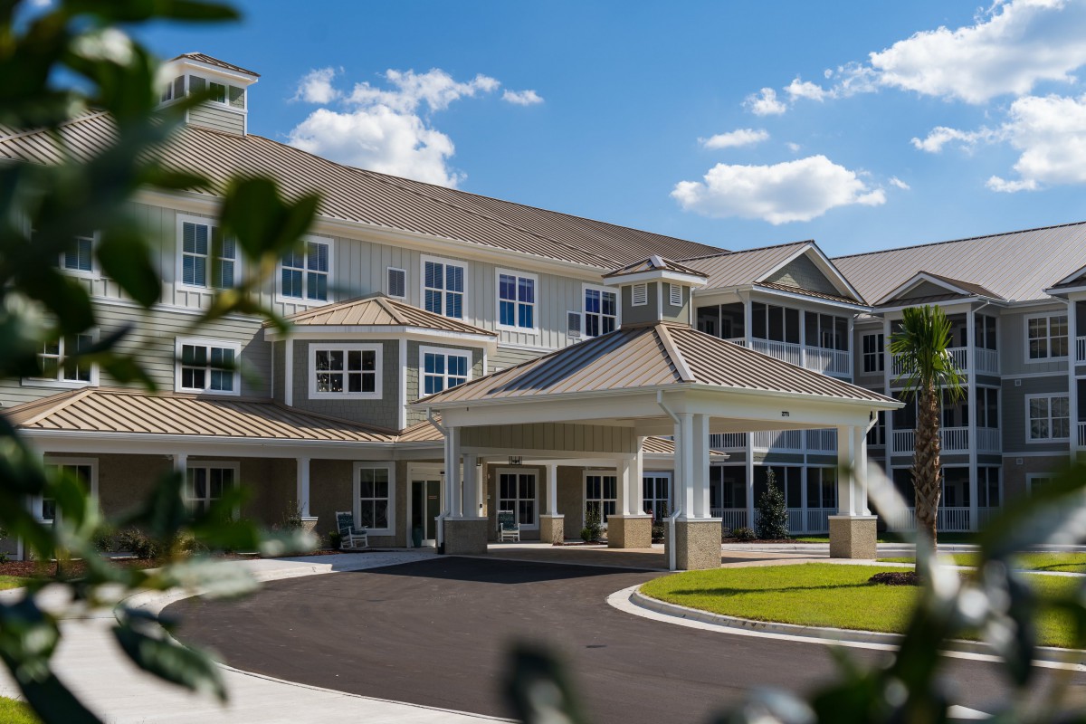 A large, multi-story residential building with a prominent entrance, surrounded by landscaped greenery.
