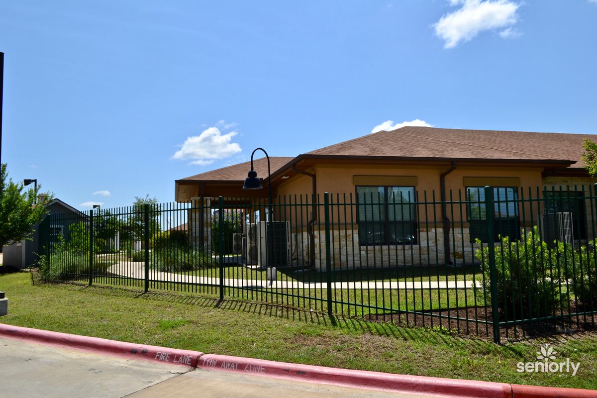 A one-story building with a fence surrounding it under a clear blue sky.