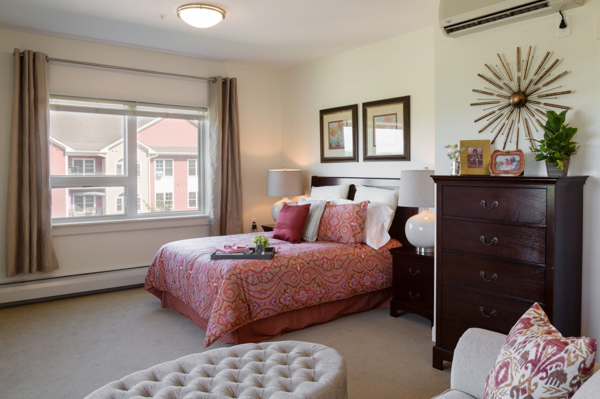 A cozy bedroom with stylish decor and a large window allowing natural light.