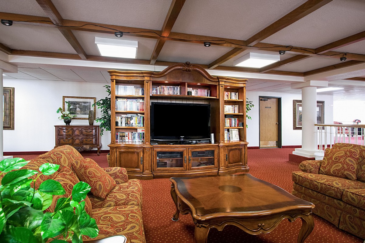 A cozy living room featuring a wooden entertainment center with bookshelves, a large television, and comfortable seating.