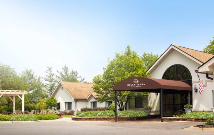 A charming building surrounded by lush greenery, featuring a spacious driveway.