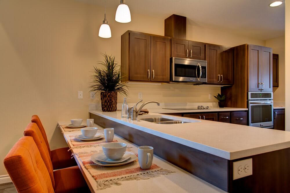 A modern kitchen with wood cabinets, stainless steel appliances, and a stylish dining area.