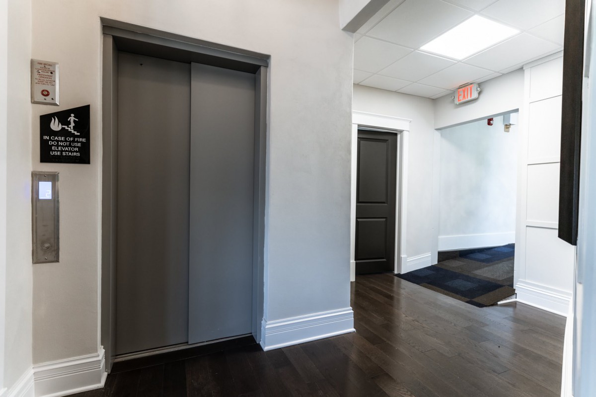 A hallway with an elevator and adjacent doors in a building interior.