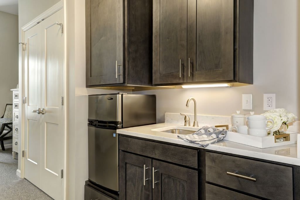 A modern kitchen with dark cabinets, stainless steel appliances, and under-cabinet lighting.