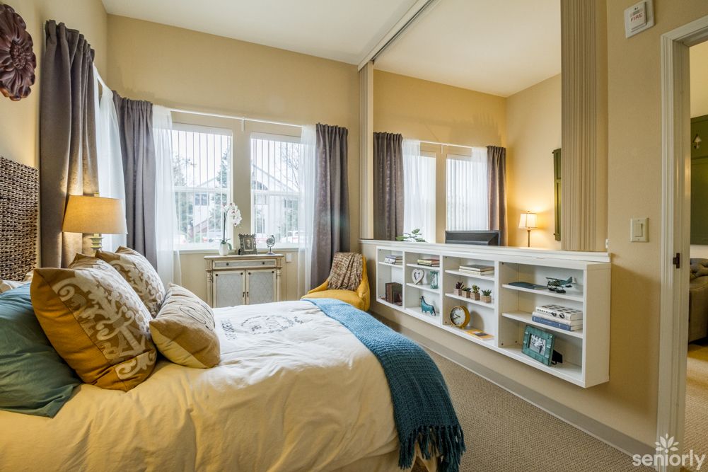 A cozy bedroom with soft lighting, elegant decor, and a large mirror reflecting natural light.