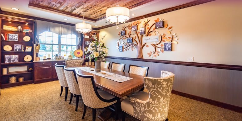 A beautifully decorated dining room featuring a wooden table, upholstered chairs, and wall art depicting a family tree.