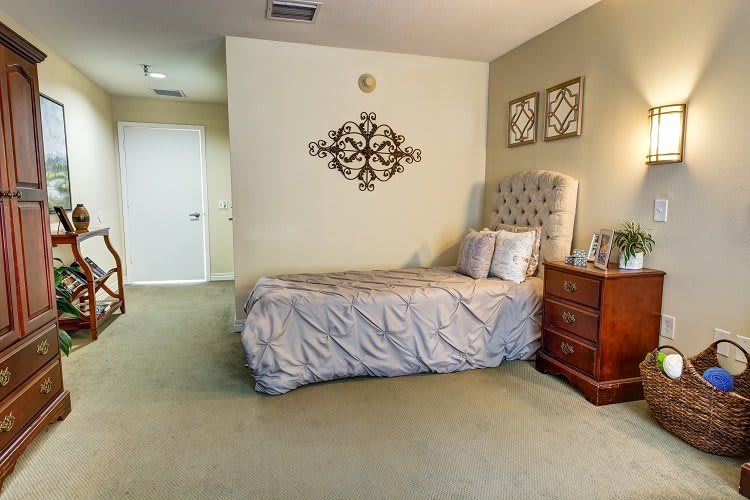A cozy bedroom with a single bed, decorative pillows, and artwork on the walls.