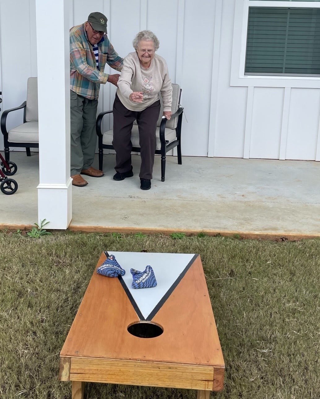Two seniors enjoying a game of cornhole outdoors.