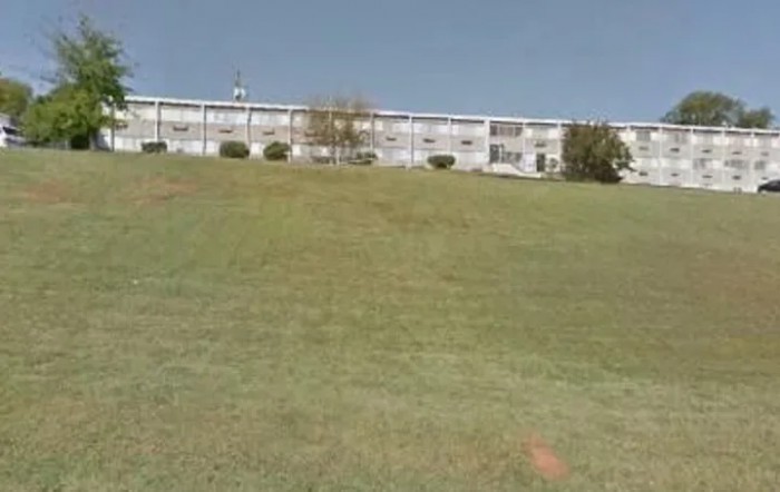 A building at the top of a grassy hill under a clear sky.
